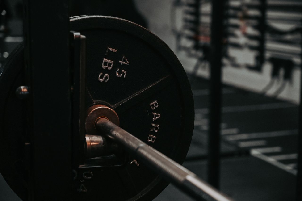 Detailed close-up of a heavy barbell loaded with a 45 lbs weight plate in a gym setting.